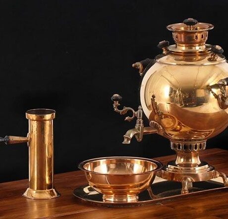 Polished brass samovar with bowl and accessory on a wooden table