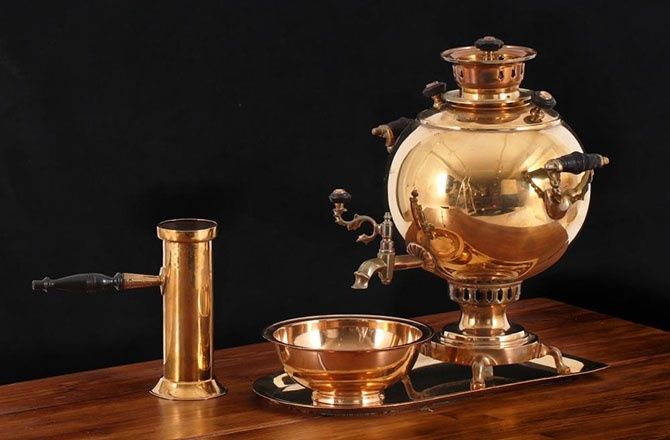 Polished brass samovar with bowl and accessory on a wooden table