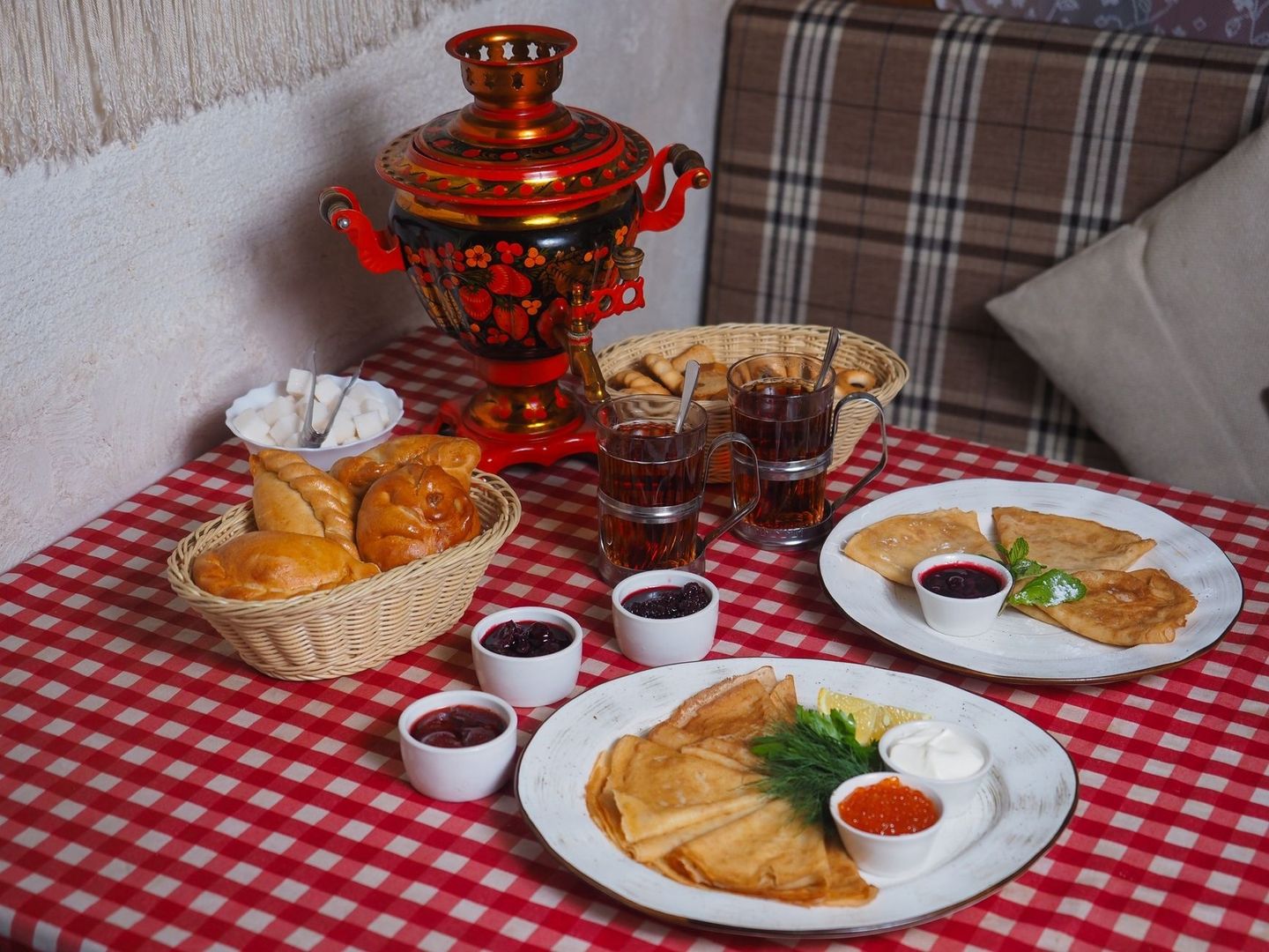 Decorated Russian samovar with tea, pastries, and pancakes on a table